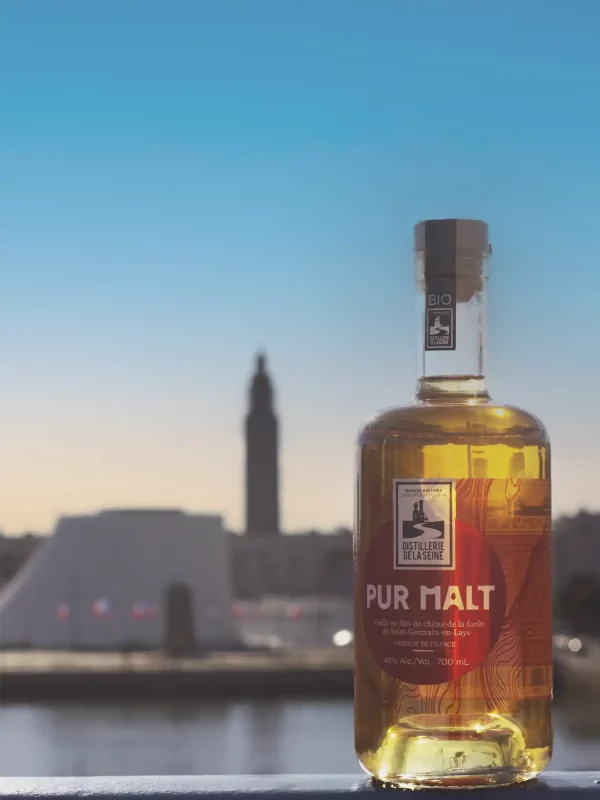 Bouteille de pur malt poser sur un pont avec en arrière plan de volcan et l'église saint joseph du havre